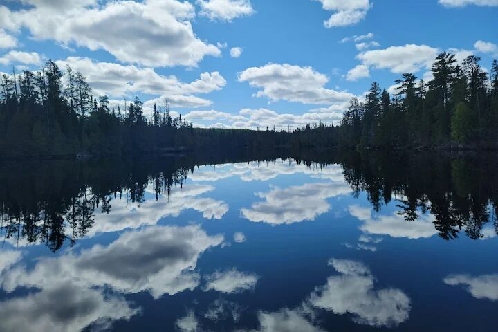 Canoe gliding across a calm lake surrounded by pine forests in the Boundary Waters Canoe Area, Minnesota